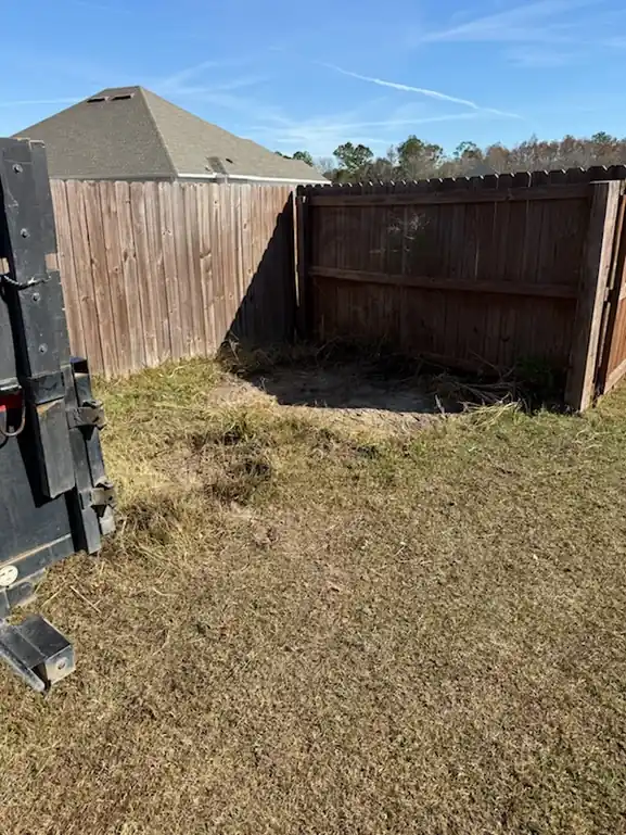 The same yard cleared back to bare ground along the fence line