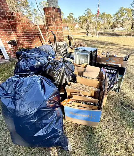 Bagged waste and flattened cardboard piled beside a brick chimney