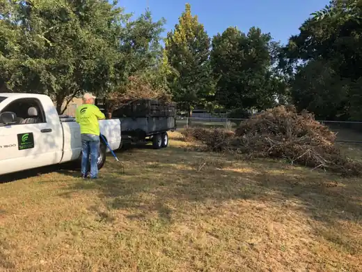 A crew member in hi-vis loading brush beside a white truck